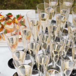 Champagne and toasts at banquet. Festive reception. Close-up of many flutes of champagne or other fizzy drink with toasts with vegetables and cream cheese at wedding reception or banquet. Festive reception.
